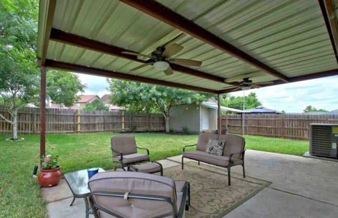 This image shows a metal patio cover over a patio with a back yard in the background in Fuquay-Varina, North Carolina.